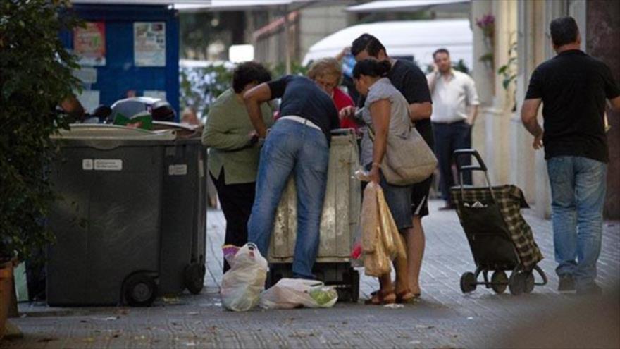 Varias personas recogen comida caducada de los contenedores de un supermercado, en Barcelona (España).
