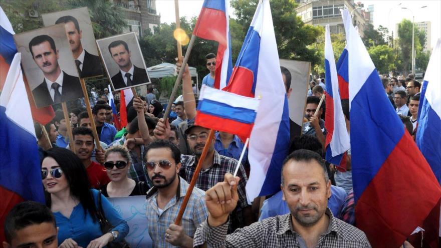 Cientos de personas sostienen pancartas con la imágen del presidente sirio, Bashar al-Asad, y banderas rusas cerca de la embajada de Rusia en Damasco, Siria, 13 de octubre de 2015.