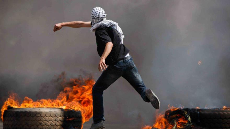 Un manifestante palestino lanza piedras contra soldados israelíes.