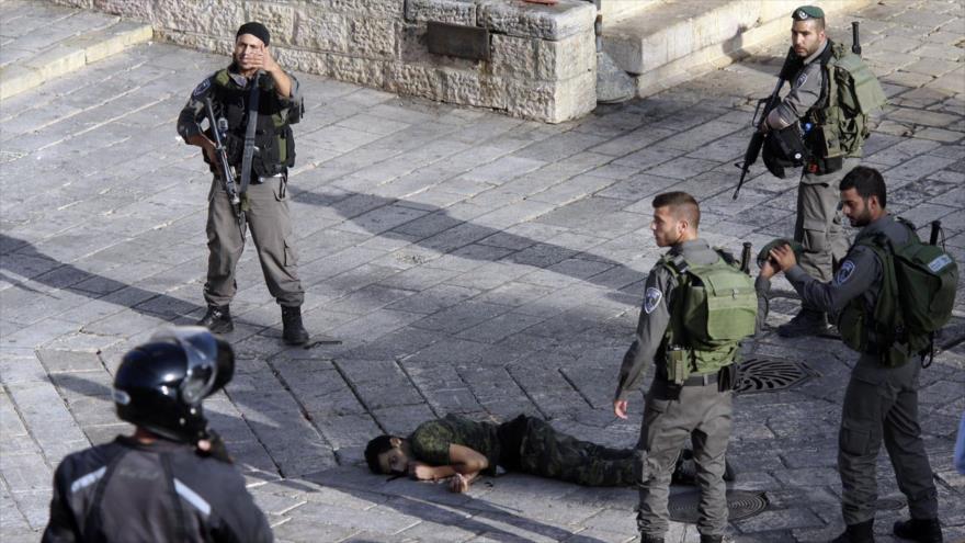 Soldados israelíes rodean a un palestino tiroteado que yace en el suelo, en Al-Quds (Jerusalén).