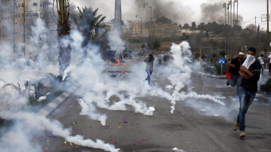 Manifestantes palestinos huyen de los gases lacrimógenos lanzados por las fuerzas israelíes durante enfrentamientos en Cisjordania, 23 de octubre de 2015.