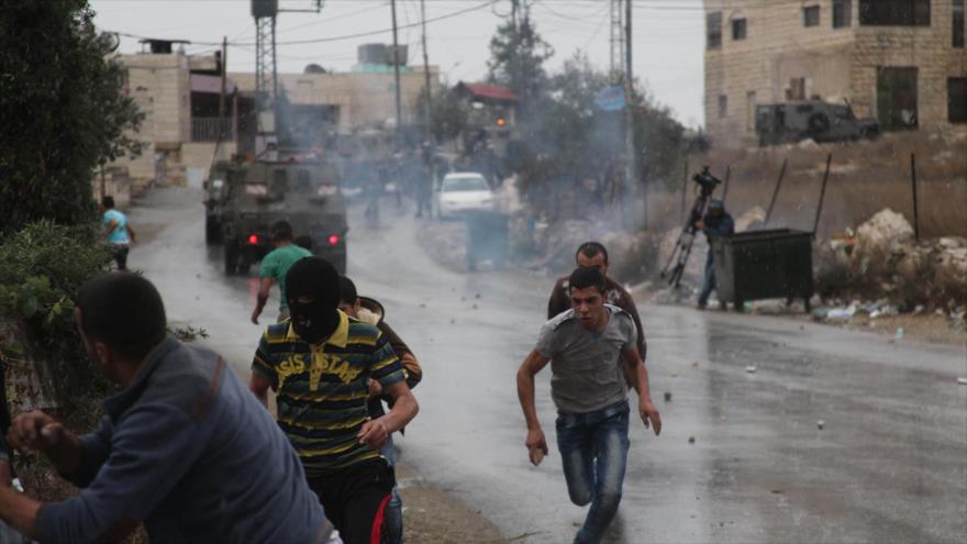 Palestinos escapan de los gases lacrimógenos disparados por soldados israelíes durante los enfrentamientos en Cisjordania.