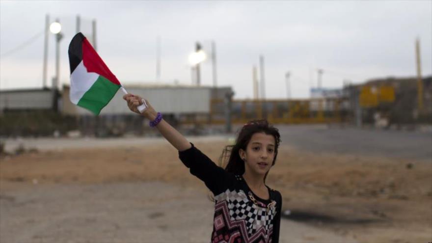 Una niña sostiene una bandera palestina en un territorio ocupado. 