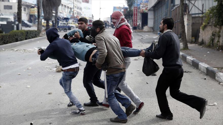 Civiles portan a un palestino herido por balas israelíes en la ciudad de Al-Jalil, 30 de octubre de 2015.