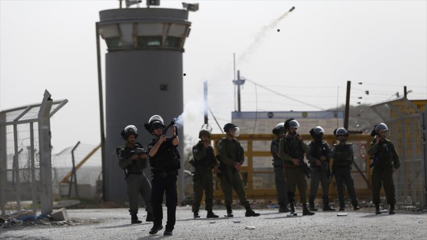 Soldado israelí lanza gas lacrimógeno contra los manifestantes palestinos en la ciudad cisjordana de Betunia.