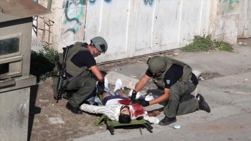 Fuerzas israelíes inspeccionan un palestino muerto a tiros en Cisjordania.