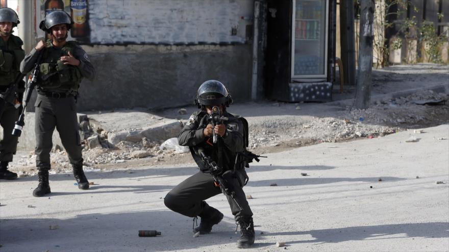 Soldado israelí apunta contra manifestantes palestinos en la ciudad de Al-Quds (Jerusalén).