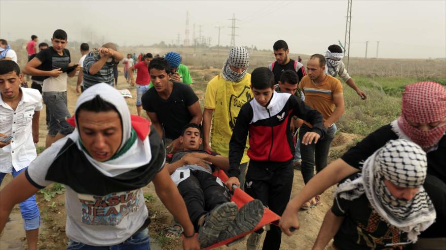 Manifestantes en la Franja de Gaza trasladan a un palestino herido por disparos de las fuerzas israelíes desplegadas cerca del enclave costero, 23 de octubre de 2015.
