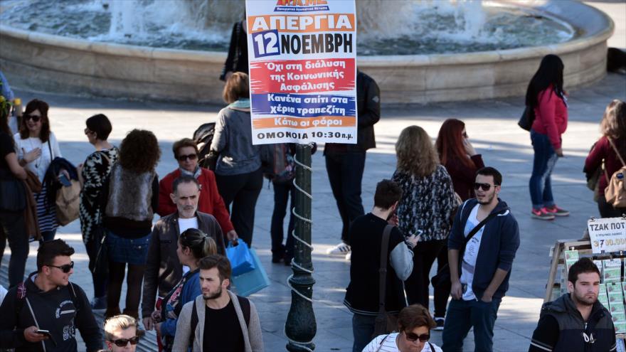 Varias personas pasan al lado de una pancarta en el que convoca a una huelga general en Atenas, capital helena. 11 de noviembre de 2015