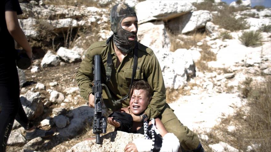 Un soldado israelí detiene a un niño palestinos durante una protesta contra los asentamientos ilegales israelíes en la aldea Nabi Sale, cerca de la ciudad cisjordana de Ramalá.