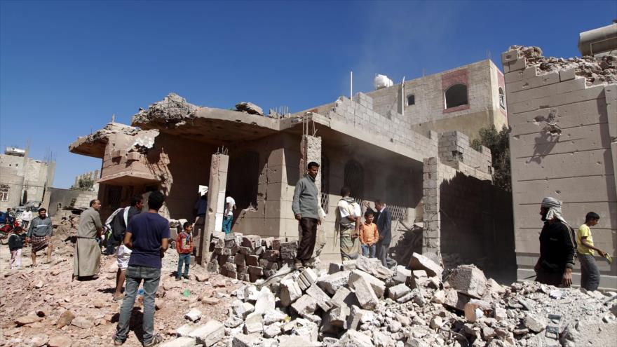 Hombres yemeníes caminan más allá de un edificio, destruido durante un ataque aéreo saudí, en la capital Saná, 29 de noviembre de 2015.