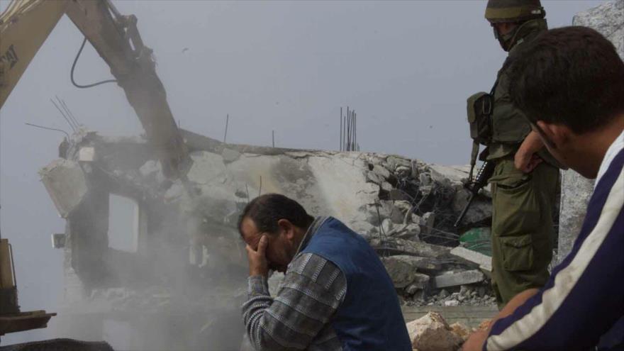 Un buldócer del ejército israelí demuele la casa de un palestino en presencia de su propietario en la Cisjordania ocupada.