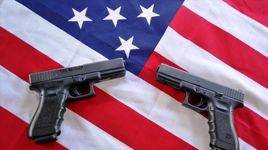 Dos pistolas colocadas sobre la bandera estadounidense.