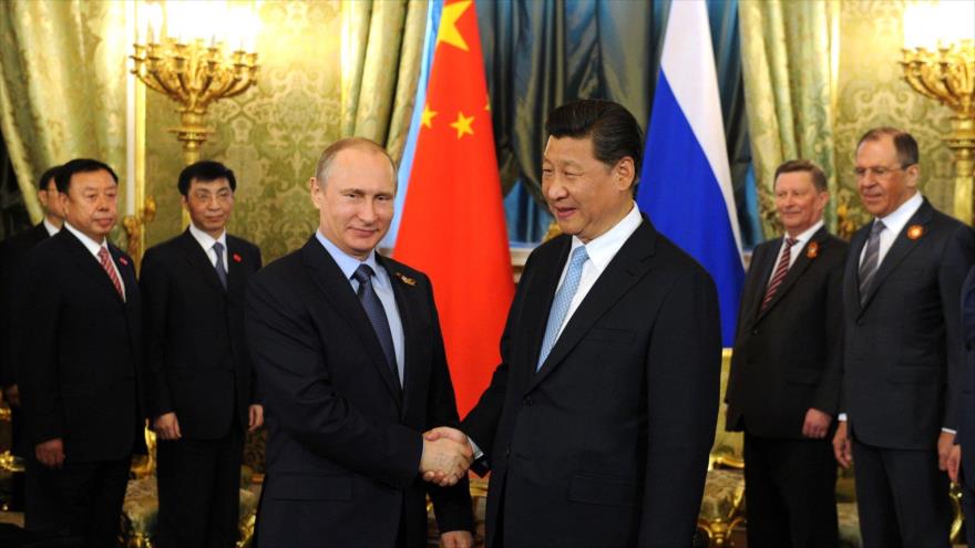 El presidente ruso, Vladimir Putin (izda.), estrecha la mano de su homólogo chino, Xi Jinping.