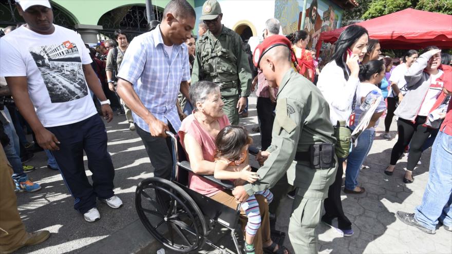Un soldado ayuda a una mujer en silla de ruedas que quiere votar en las elecciones legislativas en Caracas. 6 de Diciembre de 2015.
