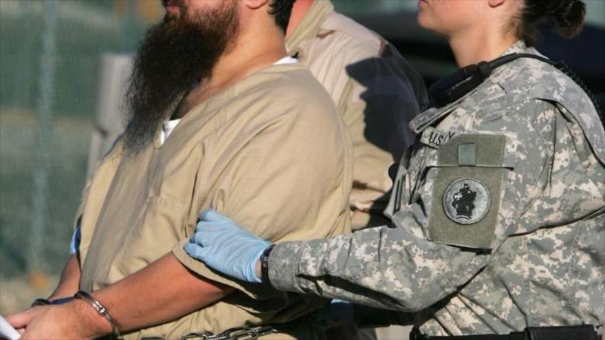 Preso de Guantánamo escoltado por una guardia femenina.
