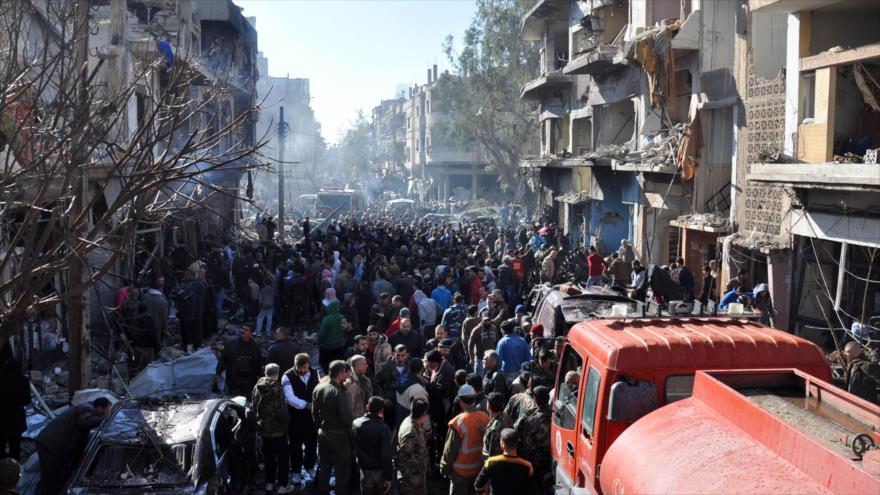 Ciudadanos sirios se reúnen en el lugar de la explosión de un coche bomba en el barrio de Al-Zahra, en Homs, en el oeste de Siria, 12 de diciembre de 2015.