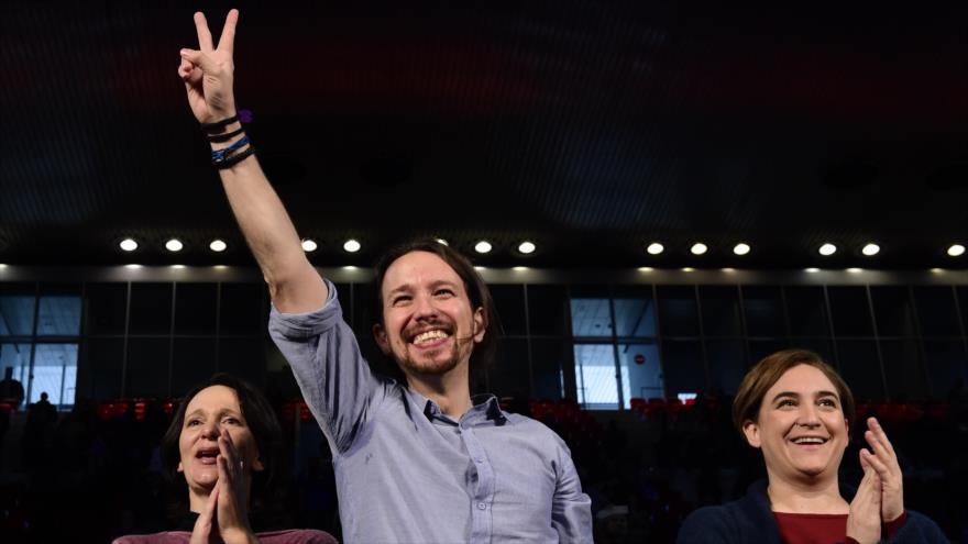 El líder de Podemos y candidato para las elecciones generales del próximo 20 de diciembre, Pablo Iglesias (centro), junto a la alcaldesa de Barcelona, Ada Colau (dcha.) y la secretaria de programas, Carolina Bescansa, saludan durante un acto de campaña en Madrid, 13 de diciembre 2015.