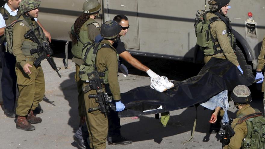 Soldados israelíes portan el cuerpo sin vida de un palestino en la ciudad de Al-Jalil (Hebrón).