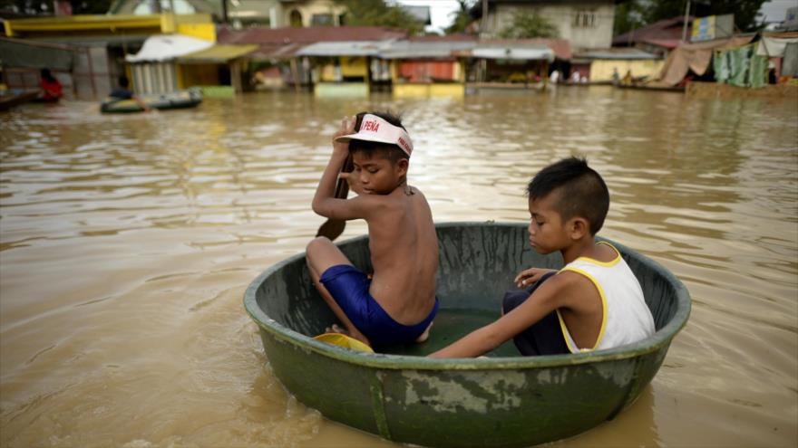 Niños filipinos cruzan un callejón inundado en Candaba, Pampanga, al norte de Manila, la capital, 18 de diciembre de 2015. 