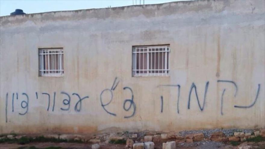 Pared de una casa palestina pintada con lemas en hebreo como "venganza", tras un ataque con granadas de humo en la localidad cisjordana de Beitillu, 22 de diciembre de 2015.