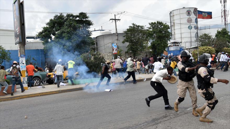 Los manifestantes huyen de los gases lacrimógenos mientras marchan para protestar contra el Consejo Electoral Provisional (CEP), los resultados de las elecciones y también para solicitar una comisión independiente para revisar el resultado de las próximas elecciones en Puerto Príncipe (capital haitiana), 16 de diciembre de 2015.