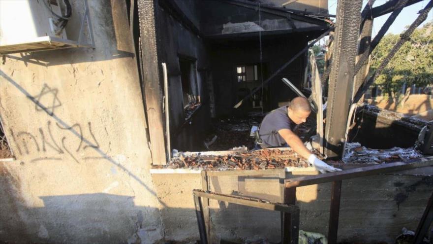 Un policía israelí inspecciona la casa quemada palestina objeto del ataque de un grupo de colonos extremistas en la aldea de Kafr Duma, cerca de la ciudad cisjordana de Nablus. 31 de julio de 2015.