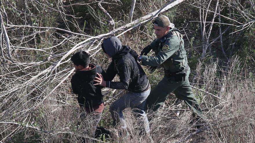 Un agente de la Patrulla Fronteriza detiene a los inmigrantes menores indocumentados cerca de la frontera entre Estados Unidos y México, 10 de diciembre de 2015 en La Grulla, Texas. 