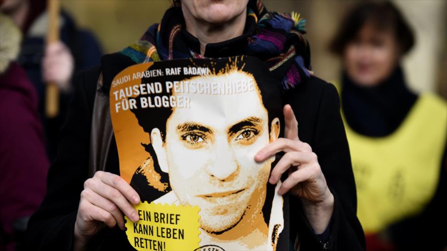 Una activista de Amnistía Internacional (AI) con una foto del activista y bloguero saudí Raif Badawi durante una protesta contra su castigo de flagelación frente a la embajada de Arabia Saudí en Berlín, capital alemana.