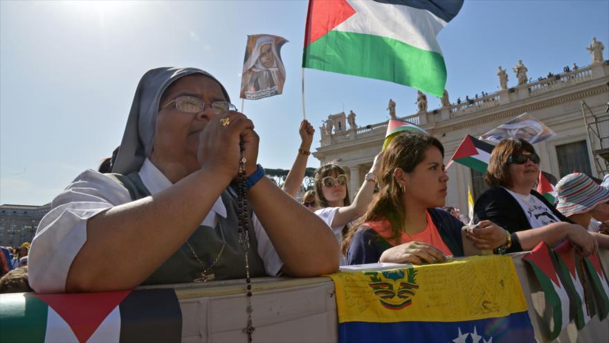 Peregrinos ondean banderas de Palestina antes de una misa en la plaza de San Pedro del Vaticano, el 17 de mayo de 2015.