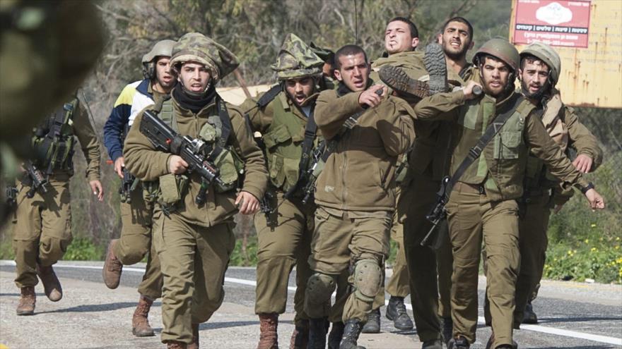 Soldados israelíes llevan en volandas a su colega herido en un ataque de Hezbolá.