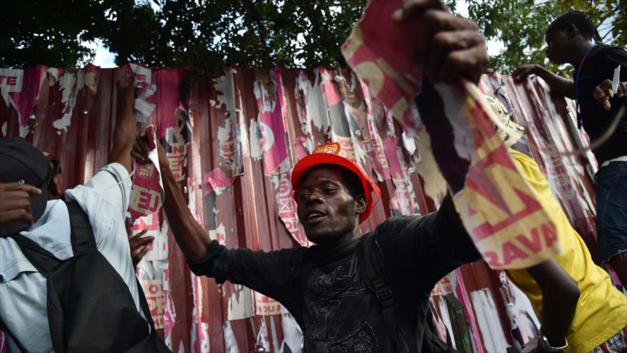 Manifestantes rasgan carteles electorales del candidato oficialistas para las presidenciales, Jovenel Moise, durante una marcha en Puerto Príncipe (capital de Haití), para protestar contra los resultados anunciados por el Consejo Electoral Provisional (CEP), 03 de diciembre de 2015.