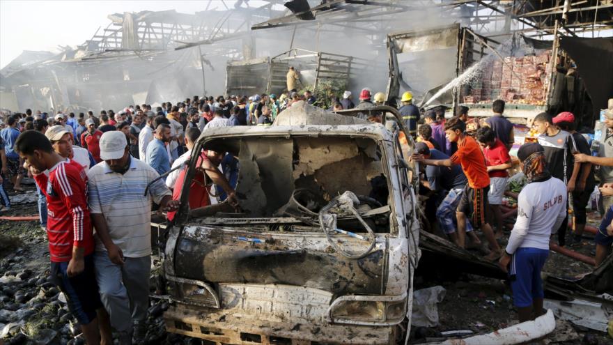 Ciudadanos iraquíes reunidos en el sitio de un ataque con coche bomba.