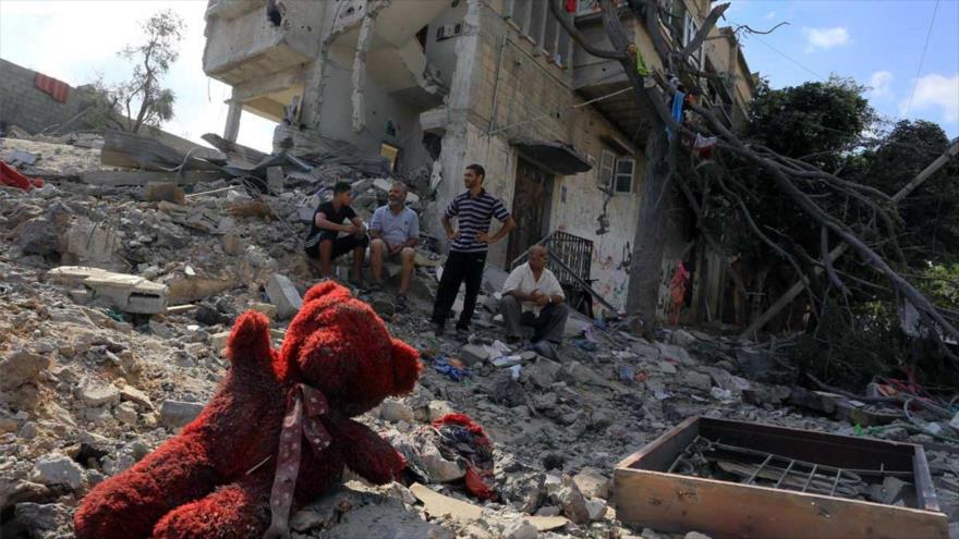 Un número de gazatíes entre los escombros de sus casas destruidas por el régimen de Israel durante la ofensiva de 51 días.