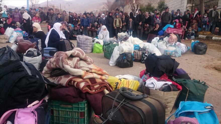 Sirios esperan la llegada de ayudas humanitarias en el pueblo asediado de Madaya, en el campo de Damasco (capital), 11 de enero de 2016.