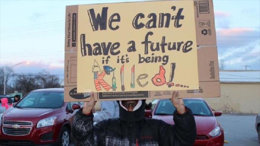 Un manifestante y miembro del movimiento Black Lives Matter, sostiene una pancarta en la que se lee: "No podemos tener futuro si esto es matado", 16 de enero de 2016.