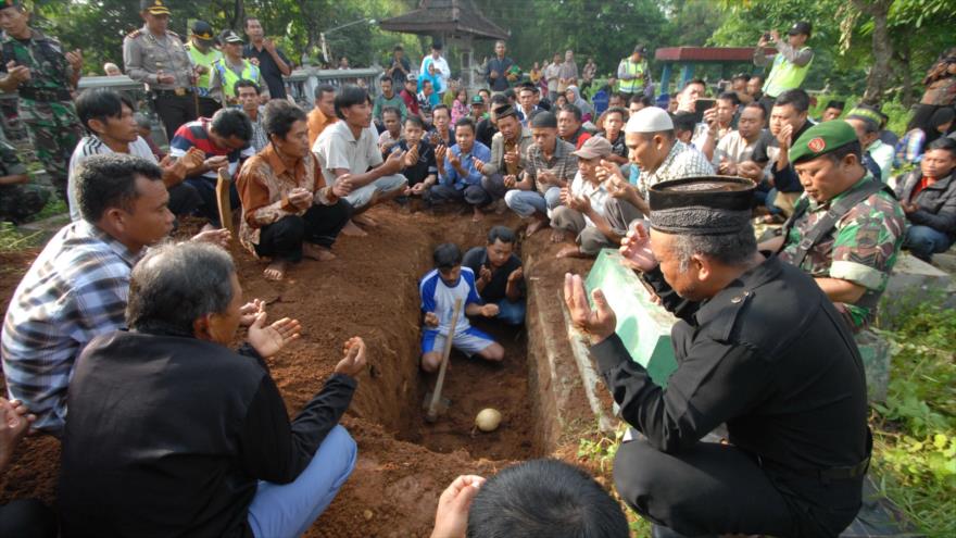 Los deudos y parientes de una víctima de los ataques de Yakarta rezan sobre su tumba durante un funeral custodiado por comandos de la Policía en un cementerio en Boyolali, isla central de Java de Indonesia, 17 de enero de 2016.