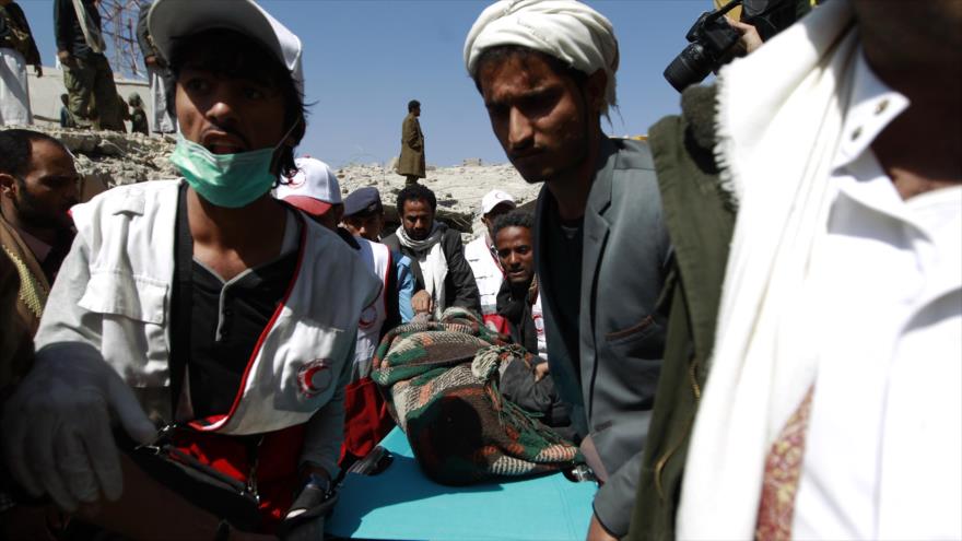 Rescatistas yemeníes llevan el cuerpo de un agente que fue recuperado de los escombros de la sede de la policía en Saná, la capital, destruida por un ataque aéreo saudí, 18 de enero de 2016.