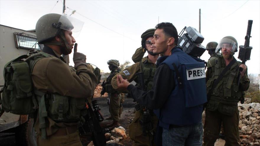 Las fuerzas de seguridad del régimen israelí mandan callar a un reportero.