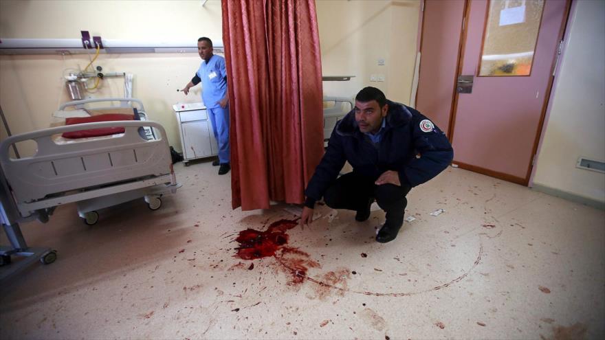 Un médico examina la mancha de sangre dejada por un palestino que fue asesinado por fuerzas secretas israelíes durante una agresión al Hospital Al-Ahli en la ciudad cisjordana de Al-Jalil (Hebrón), 12 de noviembre de 2015.