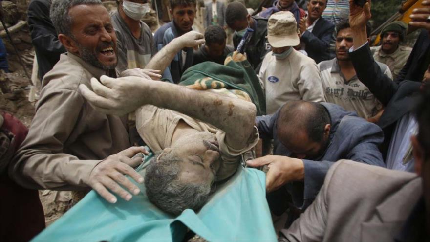 Los yemeníes trasladan el cuerpo sin vida de un hombre hallado bajo los escombros de las casas destruidas por los ataques aéreos saudíes contra la ciudad vieja de Saná, capital de Yemen.