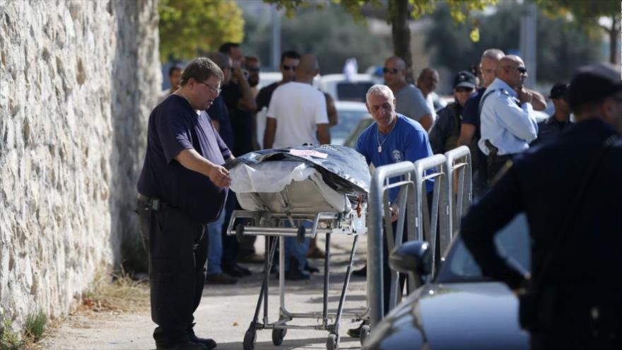 Médicos israelíes trasladan un palestino muerto en la ciudad de Al-Quds.
