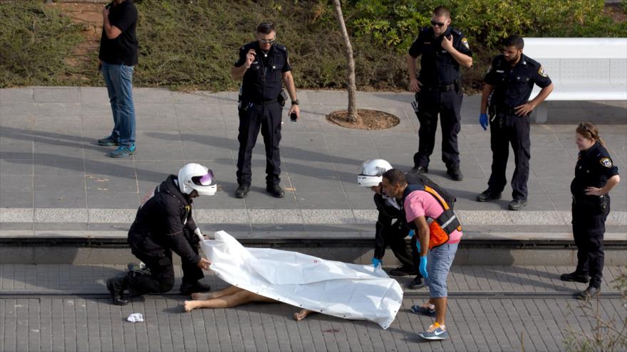 Militares israelíes cubren el cuerpo sin vida de un palestino en la ciudad de Al-Quds.