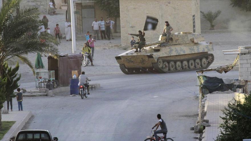Residentes de la ciudad de Al-Raqa (norte de Siria) miran un desfile del grupo terrorista EIIL (Daesh, en árabe), 30 de junio de 2014.