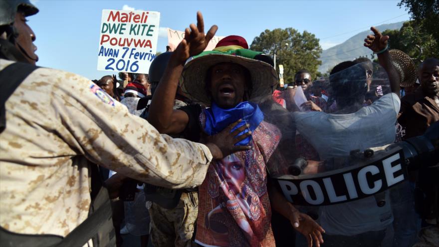 Haitianos tratan de romper la barrera policial extendida en todo el perímetro del Palacio Nacional durante una marcha en Puerto Príncipe (capital) en rechazo a la intervención mediadora de la OEA en la crisis electoral, 29 de enero de 2016.