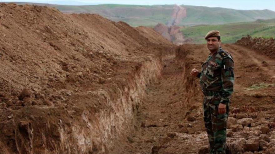 Combatiente Peshmerga vigila las zanjas excavadas en el territorio iraquí.