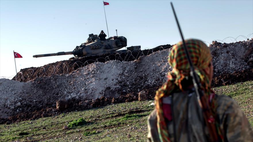Un combatiente de las Unidades de Protección Popular (YPG) frente a un tanque del Ejército de Turquía.