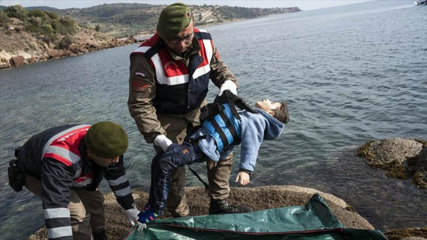 Policías turcos colocan en una bolsa el cuerpo de un niño ahogado en la costa de Turquía.