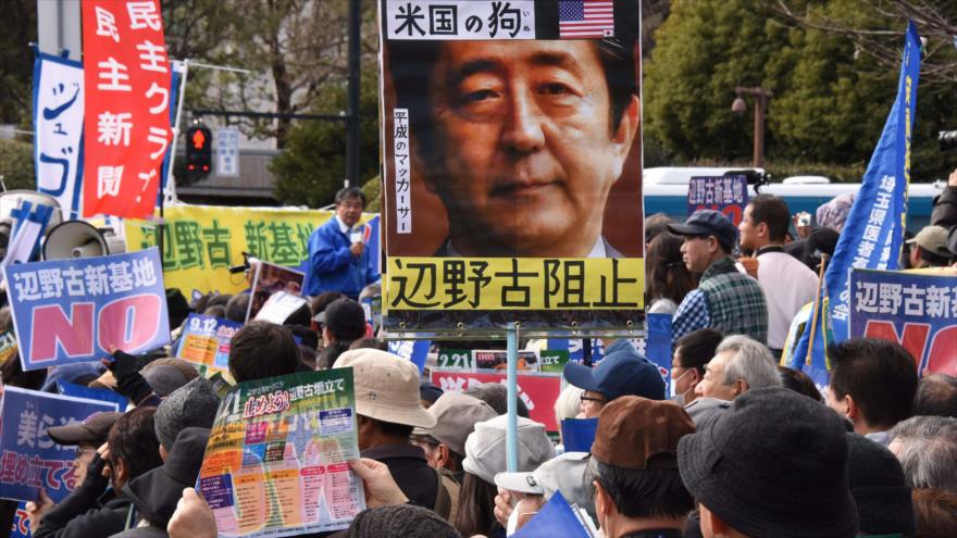 Japoneses, enarbolando pancartas, denuncian la reanudación de las obras para trasladar la base aérea estadounidense en la isla de Okinawa. Tokio, 21 de febrero de 2016