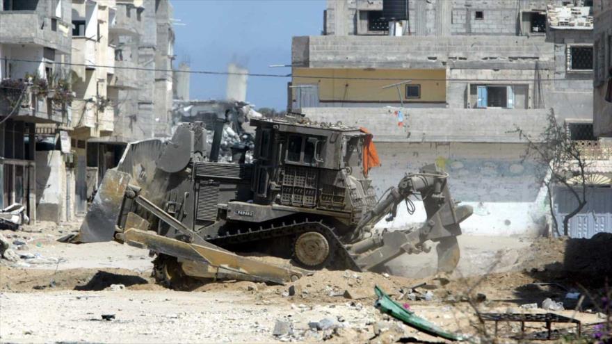 Una excavadora israelí intenta demoler una casa palestina en Cisjordania.